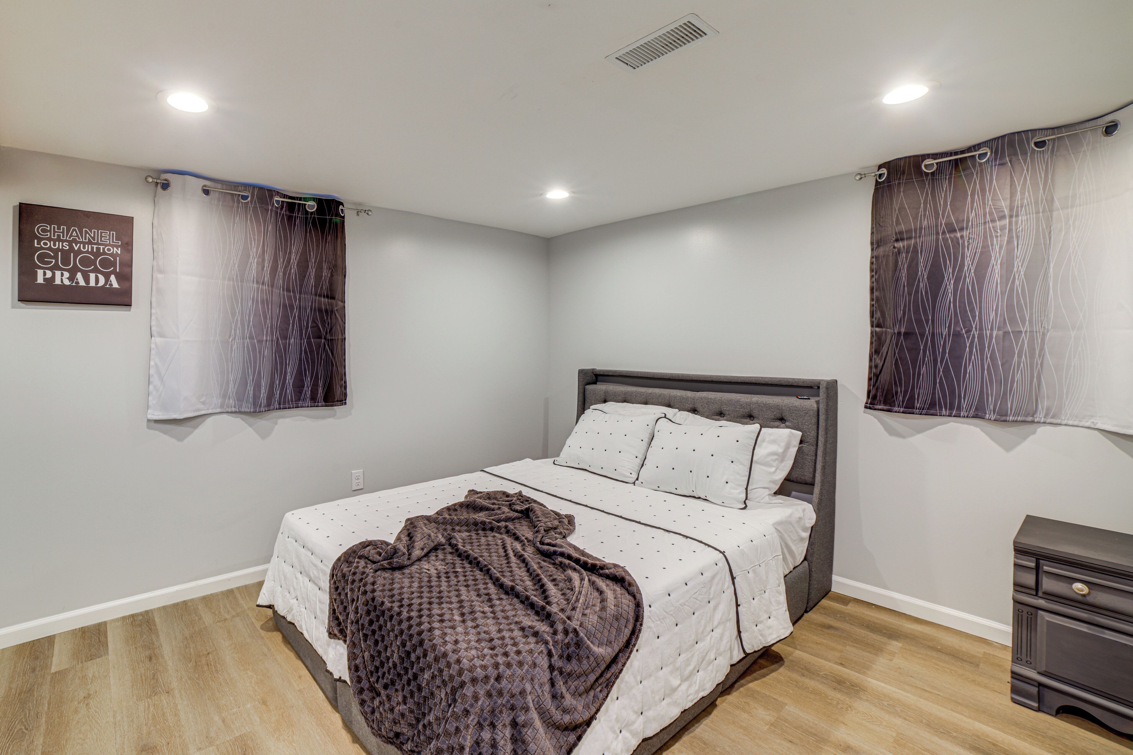 A bedroom with a bed, a nightstand, and a wall-mounted sign.