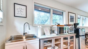 Een moderne keuken met een roestvrijstalen spoelbak, een koffiezetapparaat en een koelkast.