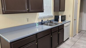 A kitchen with dark brown cabinets, a stainless steel sink, a microwave, and a dishwasher.