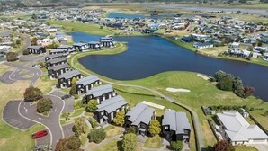 A residential area with houses, a lake, and a golf course. - Dunes Lake View Apartment (Matarangi)