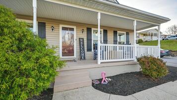 A house with a porch, a welcome sign, and a pink ribbon.
