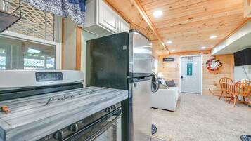 A compact kitchen with a stove, refrigerator, and a dining area with a table and chairs.