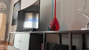 Ein modernes Wohnzimmer mit einem Flachbildfernseher, einer dekorativen Vase und einem Bücherregal.