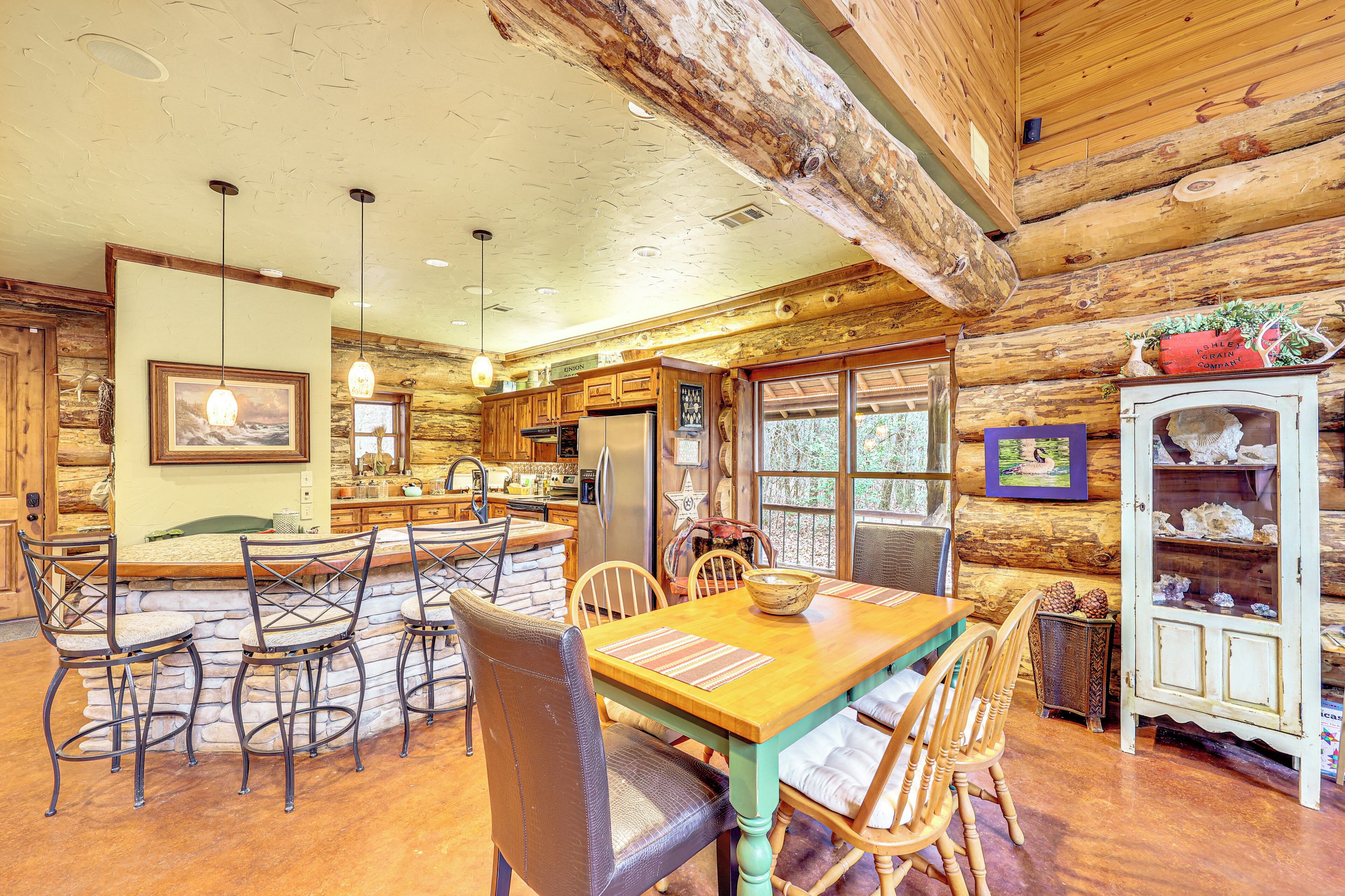 L’intérieur d’un chalet rustique en rondins de bois comprend un coin repas, une cuisine et un meuble vitrine.