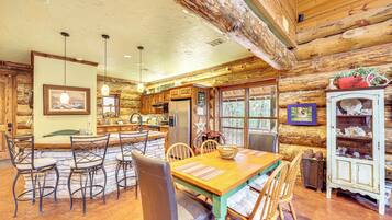 L’intérieur d’un chalet rustique en rondins de bois comprend un coin repas, une cuisine et un meuble vitrine.
