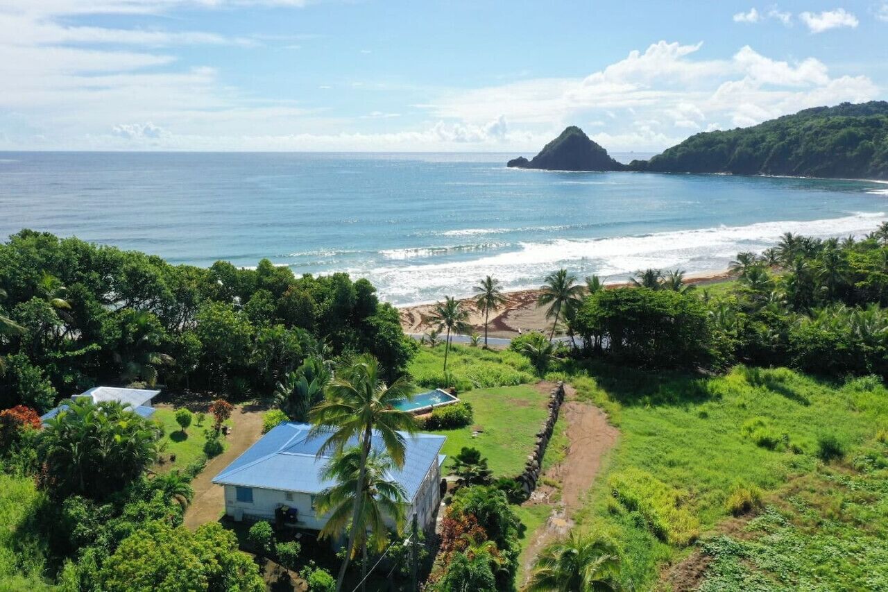 Ein Küstenanwesen mit Schwimmbad, üppiger Vegetation und Blick auf das Meer und eine kleine Insel.