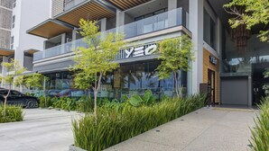 A modern building with a glass facade, a visible sign with the letters "YEO", and a parking area with a black car. - Punto Novo Nuevo Vallarta Condos (Nuevo Nayarit)