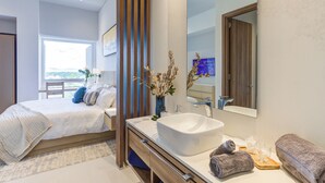 A modern bedroom with a large bed, a vanity with a large sink, and a large mirror. - Punto Novo Nuevo Vallarta Condos (Nuevo Nayarit)