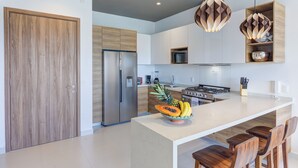 A modern kitchen with a central island, stainless steel appliances, and wooden cabinetry. - Punto Novo Nuevo Vallarta Condos (Nuevo Nayarit)