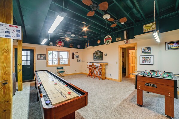 A room with a foosball table, pool table, and ceiling fans.