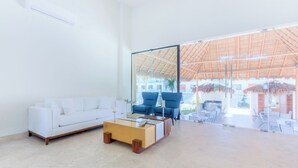 Amplia sala de estar con un sofá blanco, sillones azules y una mesa de centro.