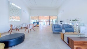 Amplia sala de estar con muebles modernos, ventanas grandes y vistas al exterior.