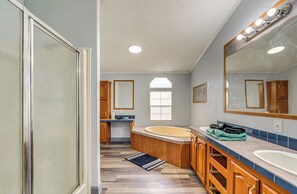 Un bagno con una vasca, uno specchio grande, mobili impiallacciati in legno e una finestra.