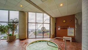 Uma área de spa com hidromassagem, janelas amplas e vista da cidade.