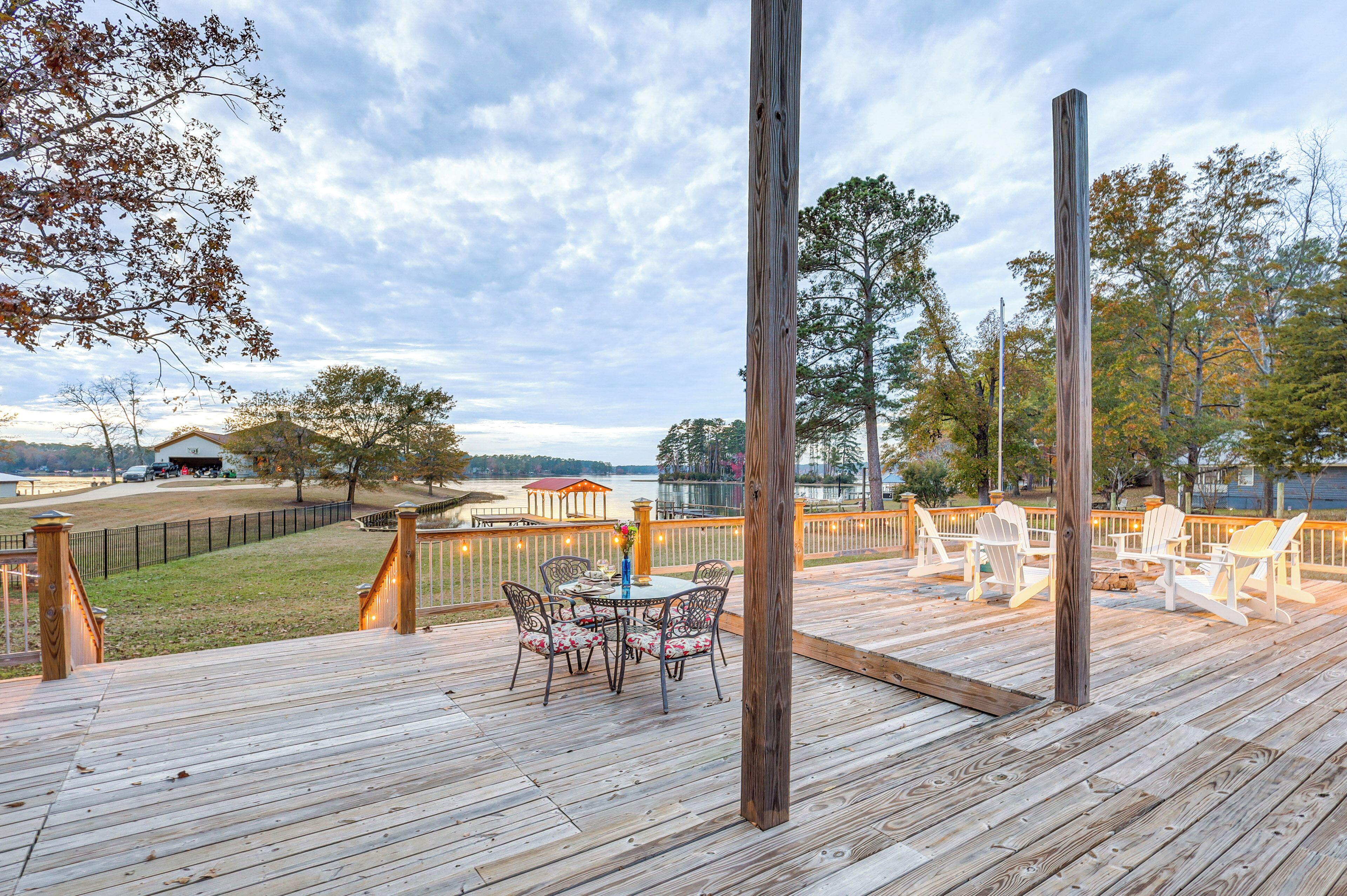Une terrasse en bois avec des meubles d’extérieur, une vue sur un lac et un belvédère en arrière-plan.