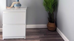 A corner of a room with a white nightstand, a blue vase with a beaded string, and a potted plant with long green leaves. - Rhythm & Blues Retreat near Syracuse University! (Syracuse)