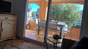 Un saló amb una porta corredissa de vidre que dona a un balcó exterior amb una taula i cadires.
