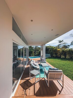 A modern outdoor deck with a pool, wooden flooring, and outdoor furniture.