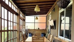 A wooden dining area with a table and chairs, large windows, and hanging pendant lights.
