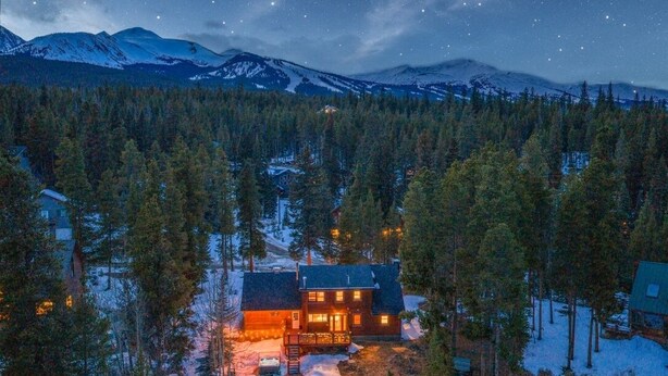 A cabin surrounded by snow-covered trees and mountains under a starry night sky. - Mtn & Lake Views, Hot Tub, Dog Friendly, Chef's Kitchen, 5 min to Main St Breck (Breckenridge)