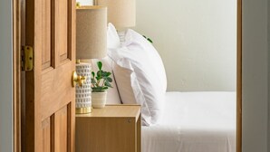 A neatly made bed with white bedding, a bedside lamp, a small potted plant, and a wooden nightstand. - Mtn & Lake Views, Hot Tub, Dog Friendly, Chef's Kitchen, 5 min to Main St Breck (Breckenridge)