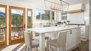 A modern kitchen with a large island, wooden deck, and mountain views. - Mtn & Lake Views, Hot Tub, Dog Friendly, Chef's Kitchen, 5 min to Main St Breck (Breckenridge)