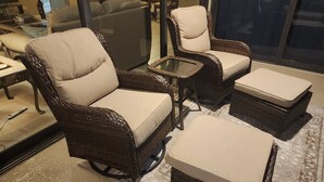 Mobilier en osier avec des sièges rembourrés et une table avec un plateau en verre, probablement dans un showroom ou le hall d’un hôtel.