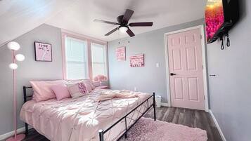 Cozy retreat with a comfortable bed, wall-mounted TV, and ceiling fan.