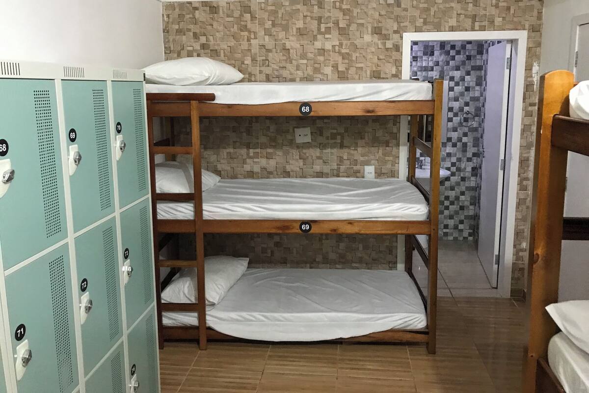A bunk bed room with lockers and a shower area.