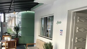 Zona de recepción con un mostrador de madera, un sofá, plantas en macetas y una ventana con vistas al exterior.