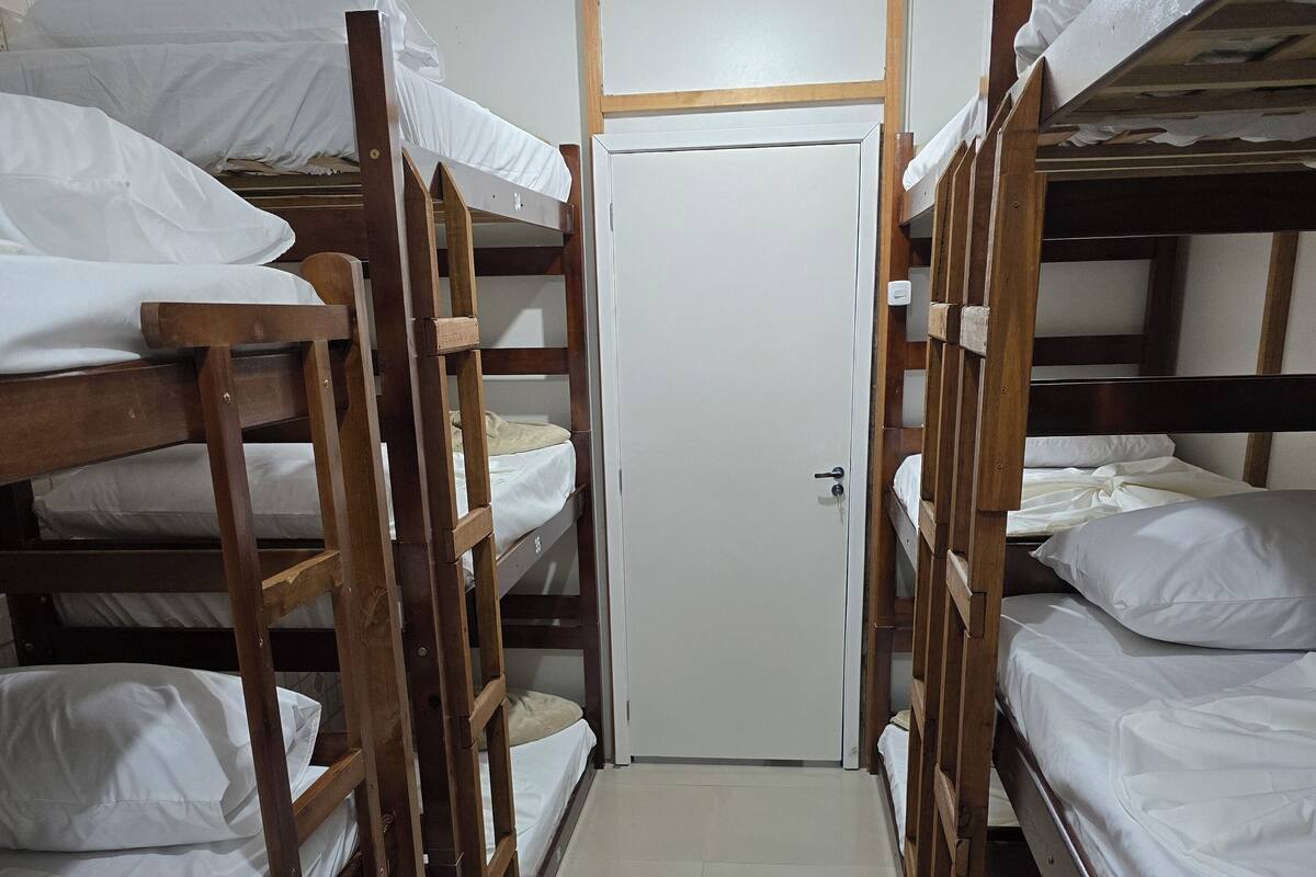 A corridor with bunk beds, a door, and a ceiling light.