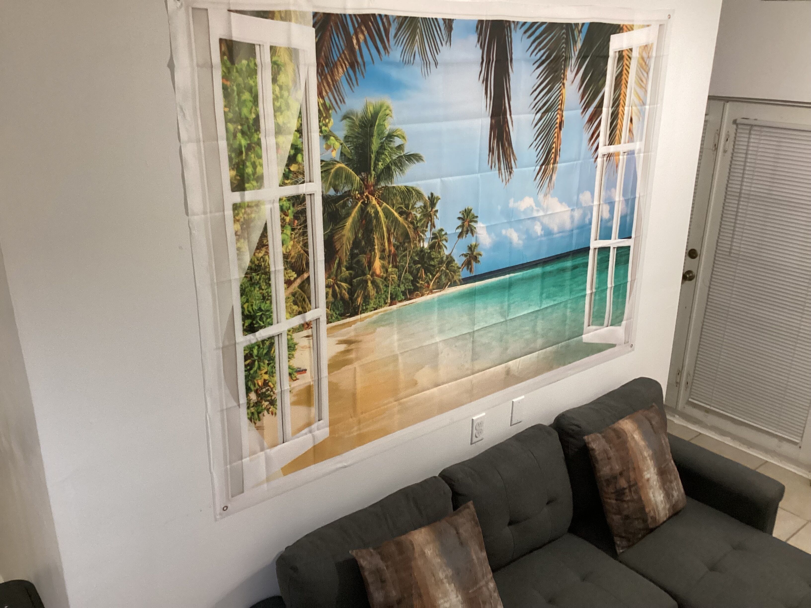 Ein Zimmer mit einem großen Fenster, das einen Blick auf eine tropische Strandlandschaft bietet.