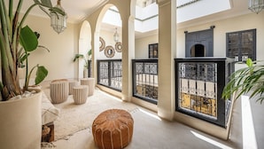 A spacious interior with high ceilings, arched doorways, and a central seating area with ottomans and a coffee table. - Riad Nayl, Luxury and Comfort 5 minutes from Jamaa El Fna (Marrakesh)