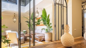 A modern living room with a wooden table, a white vase, and large green plants. - Riad Nayl, Luxury and Comfort 5 minutes from Jamaa El Fna (Marrakesh)