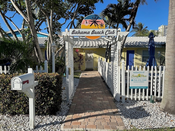 Ein Weg führt zu einem Gebäude, an dem ein Schild mit der Aufschrift "Bahama Beach Club" zu sehen ist.