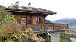 Un chalet en bois doté d’un balcon, entouré d’un feuillage automnal.