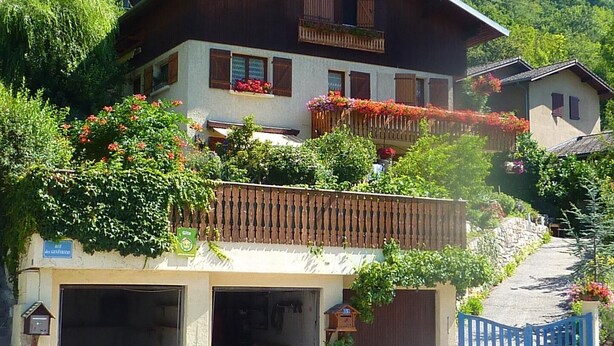 A two-story chalet with a wooden balcony, a garage, and a stone wall. - PLEIN SOLEIL - BRIDES LES BAINS (BRIDES LES BAINS)