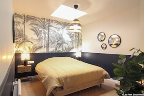 Relax in this serene bedroom with a comfortable bed, wall-mounted nightstand and lamp, and a tropical-themed tapestry.