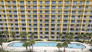 Un hôtel à plusieurs étages doté de balcons, d’une piscine et de palmiers.