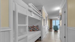 Un couloir avec un lit superposé, un ventilateur de plafond et une vue sur l’extérieur grâce à une porte vitrée.