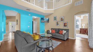 A spacious living room with two grey sofas, a glass coffee table, and a blue accent wall. - Pool, Themed Rooms, Resort (Kissimmee)