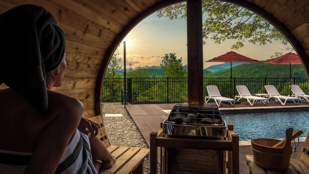 A wooden cabin with a view of a pool and lounge chairs.