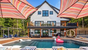 A modern house with a pool, lounge chairs, and a deck.