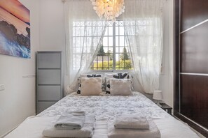Une chambre à coucher avec un lit, une fenêtre avec des rideaux, une lampe de chevet et un tableau au mur.