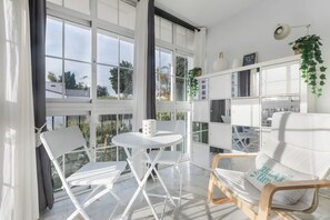 Une pièce avec une chaise blanche, une petite table ronde et une bibliothèque.