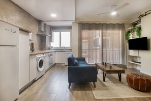 A modern apartment with a kitchen, living area, and a TV mounted on the wall.
