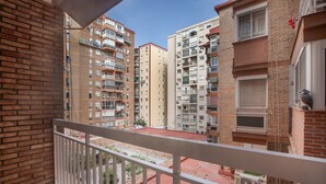 Un balcón con vistas a edificios residenciales de varios pisos, un tejado de tejas rojas y una barandilla blanca.