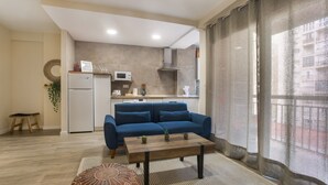 Una sala moderna con sofá, una mesita de centro y una pequeña cocina al fondo.