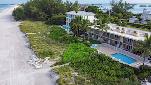 Una propiedad frente a la playa con piscina, varios balcones y abundante vegetación.
