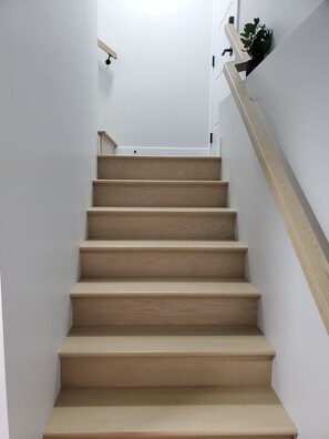 A staircase with wooden steps and a handrail, leading to a landing with a small plant. - A comfortable private 1 bedroom basement apartment for a relaxing stay. (Moncton)
